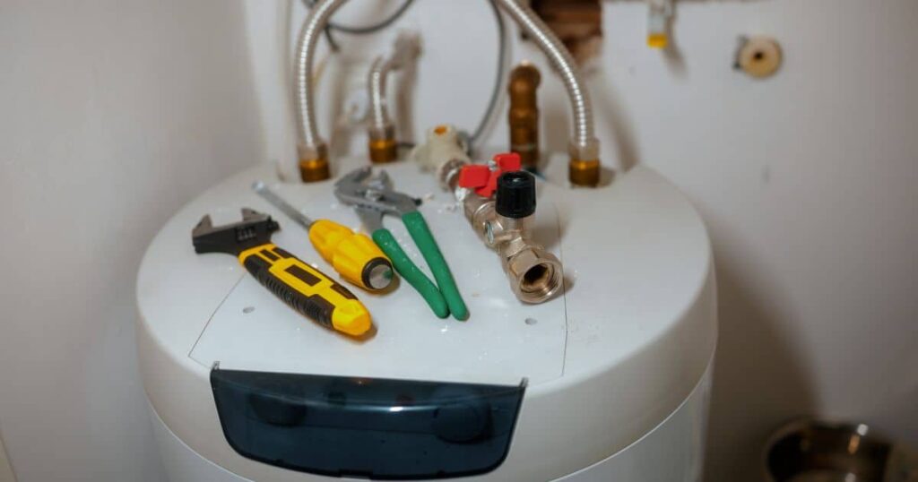 water heater with tools, two wrenches and a screwdriver with a yellow handle